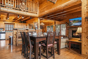 Gather around the handcrafted dining table in this stunning openconcept cabin where rustic charm meets modern comfort. Soaring logbeam ceilings, a crackling stone fireplace, and abundant natural lig