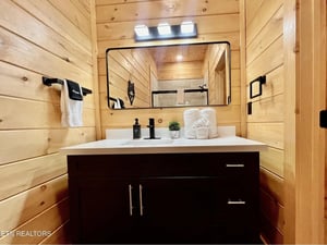 Step into your elegant wooden bathroom featuring a spacious vanity, modern fixtures, and thoughtful touches like plush towels and fresh greenery.
