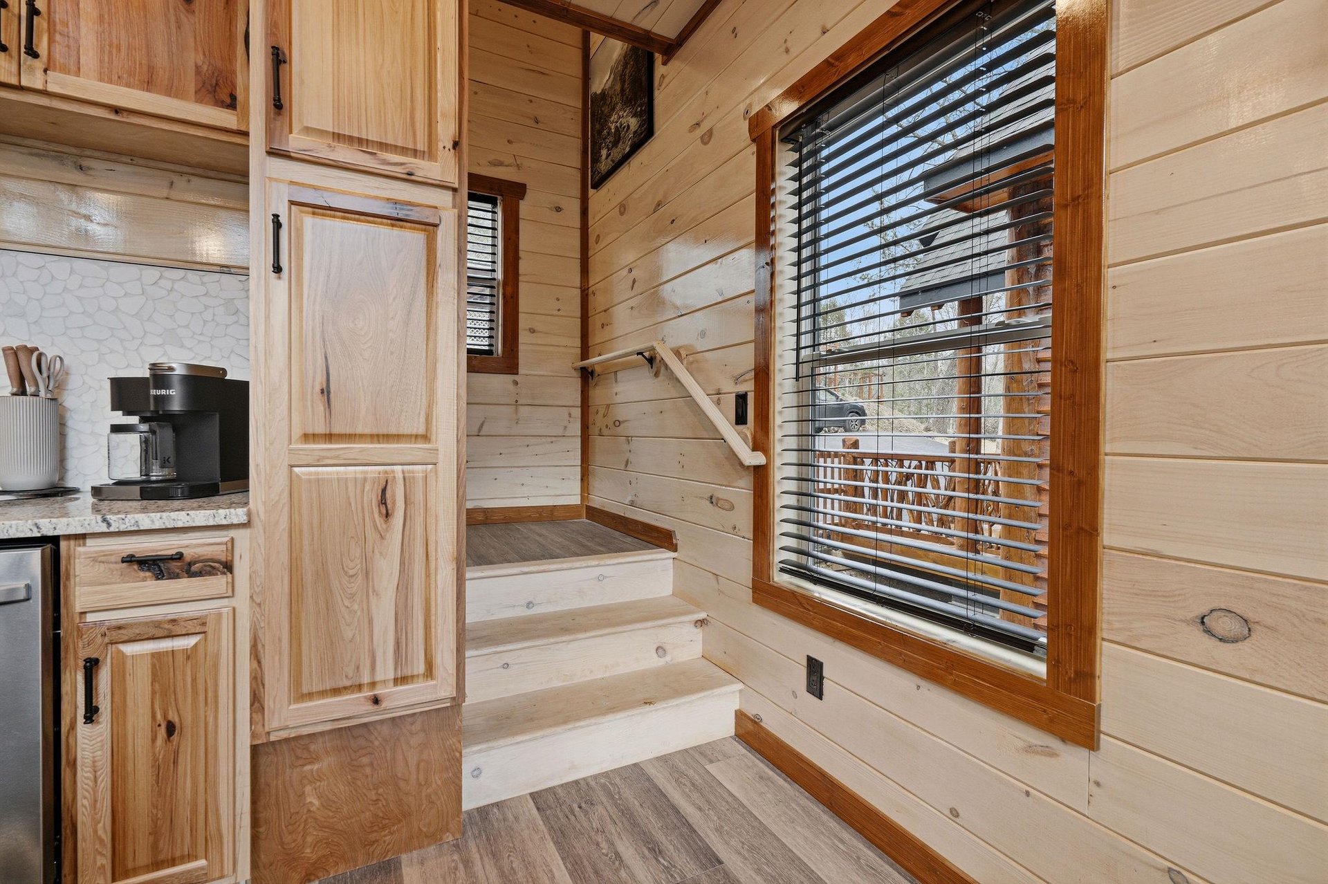 Cozy woodpaneled interior with your own kitchen featuring warm natural light streaming through windows.