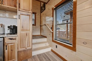 Cozy woodpaneled interior with your own kitchen featuring warm natural light streaming through windows.
