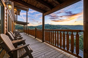 A covered deck overlooking rolling mountains at sunset—complete with rocking chairs for your evening relaxation and mountain views that stretch for miles.