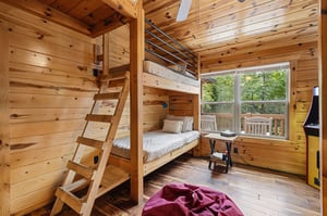 Cozy up in this charming cabin bedroom featuring sturdy bunk beds and warm wood finishes that surround you. Natural light fills the space while your private deck invites peaceful moments overlooking t