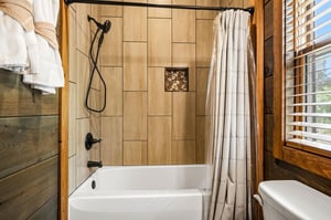 Step into your rusticmodern bathroom with natural wood accents, a sleek tiled showertub combo, and a cozy window view perfect for unwinding.