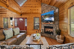 Unwind in your cozy log cabin living room, where warm wood surrounds you and a crackling stone fireplace creates the perfect atmosphere for relaxation.