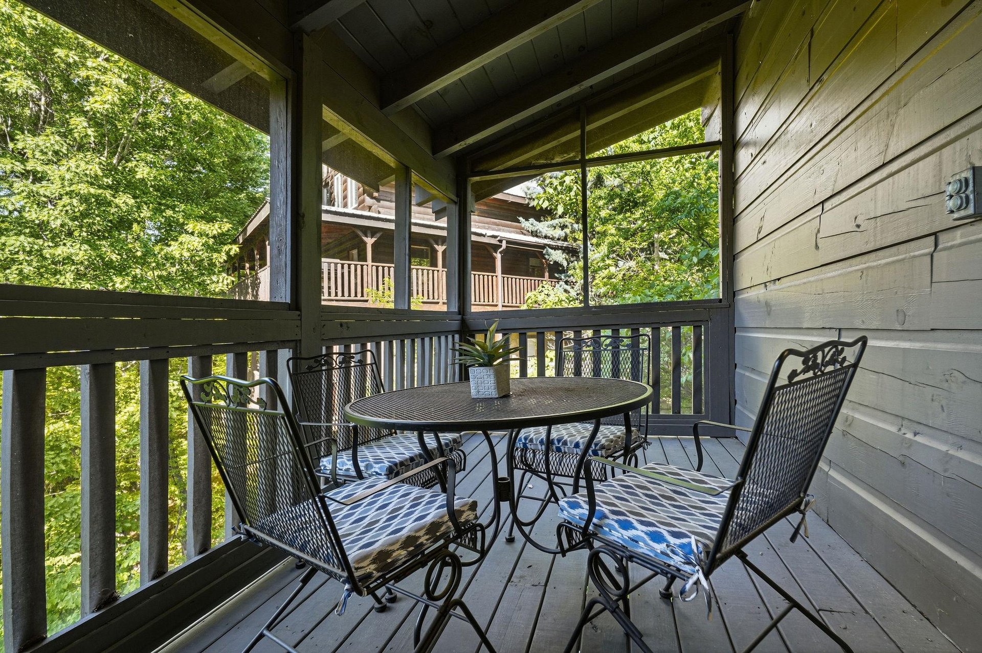 Sip your morning coffee on this covered porch, where wrought iron seating invites you to unwind surrounded by lush greenery.