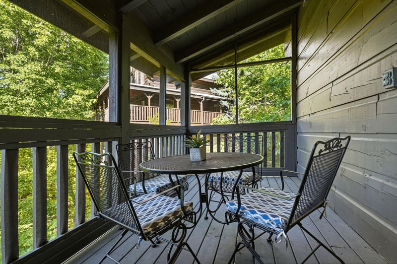 Sip your morning coffee on this covered porch, where wrought iron seating invites you to unwind surrounded by lush greenery.