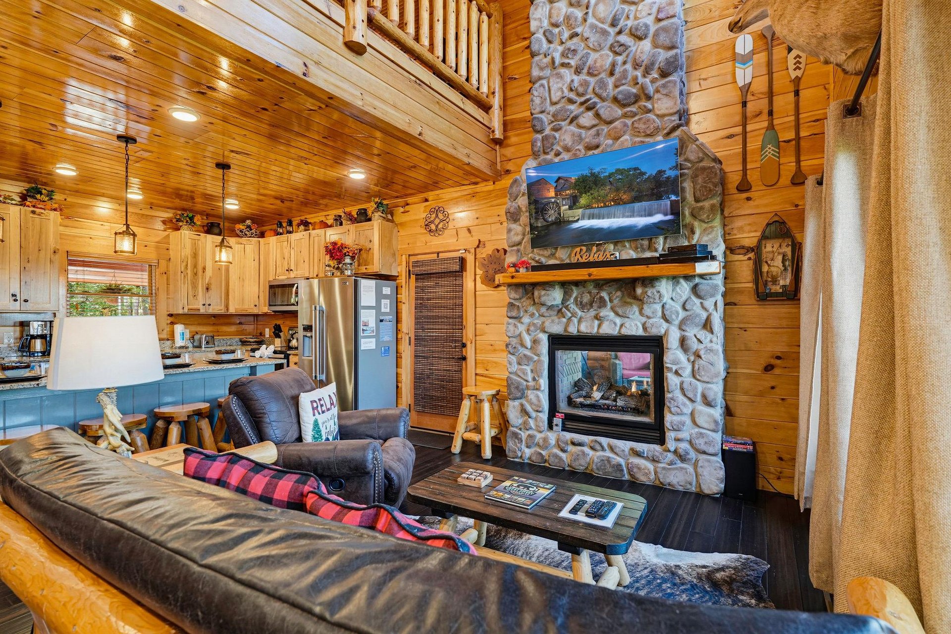 Your cozy cabin retreat awaits, where rustic charm meets modern comfort. Sink into plush seating by the stone fireplace and feel the warmth envelop you as natural wood surrounds create that perfect mo