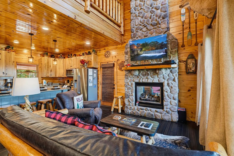 Your cozy cabin retreat awaits, where rustic charm meets modern comfort. Sink into plush seating by the stone fireplace and feel the warmth envelop you as natural wood surrounds create that perfect mo