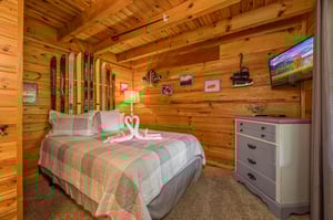 Drift off to sleep in this cozy log cabin bedroom, where rustic charm meets comfort beneath exposed wooden beams.