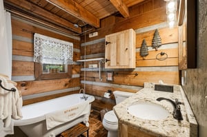 Warm wood surrounds you in this cozy cabin bathroom, where a soaking tub and granite vanity invite you to unwind after your mountain adventures.