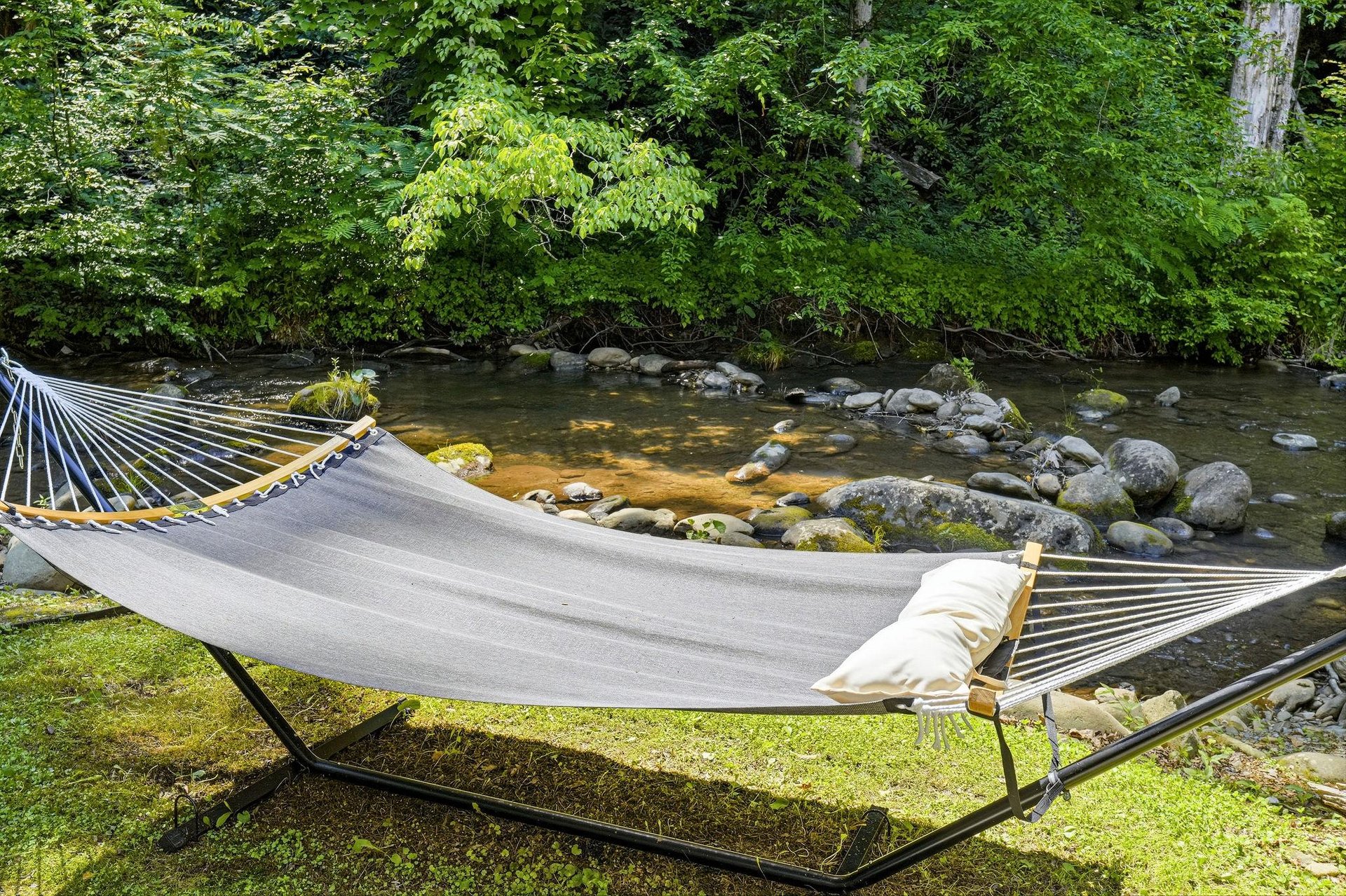Picture yourself swaying gently in this hammock as the river babbles by, sunlight filtering through lush greenery, inviting you to unwind completely.