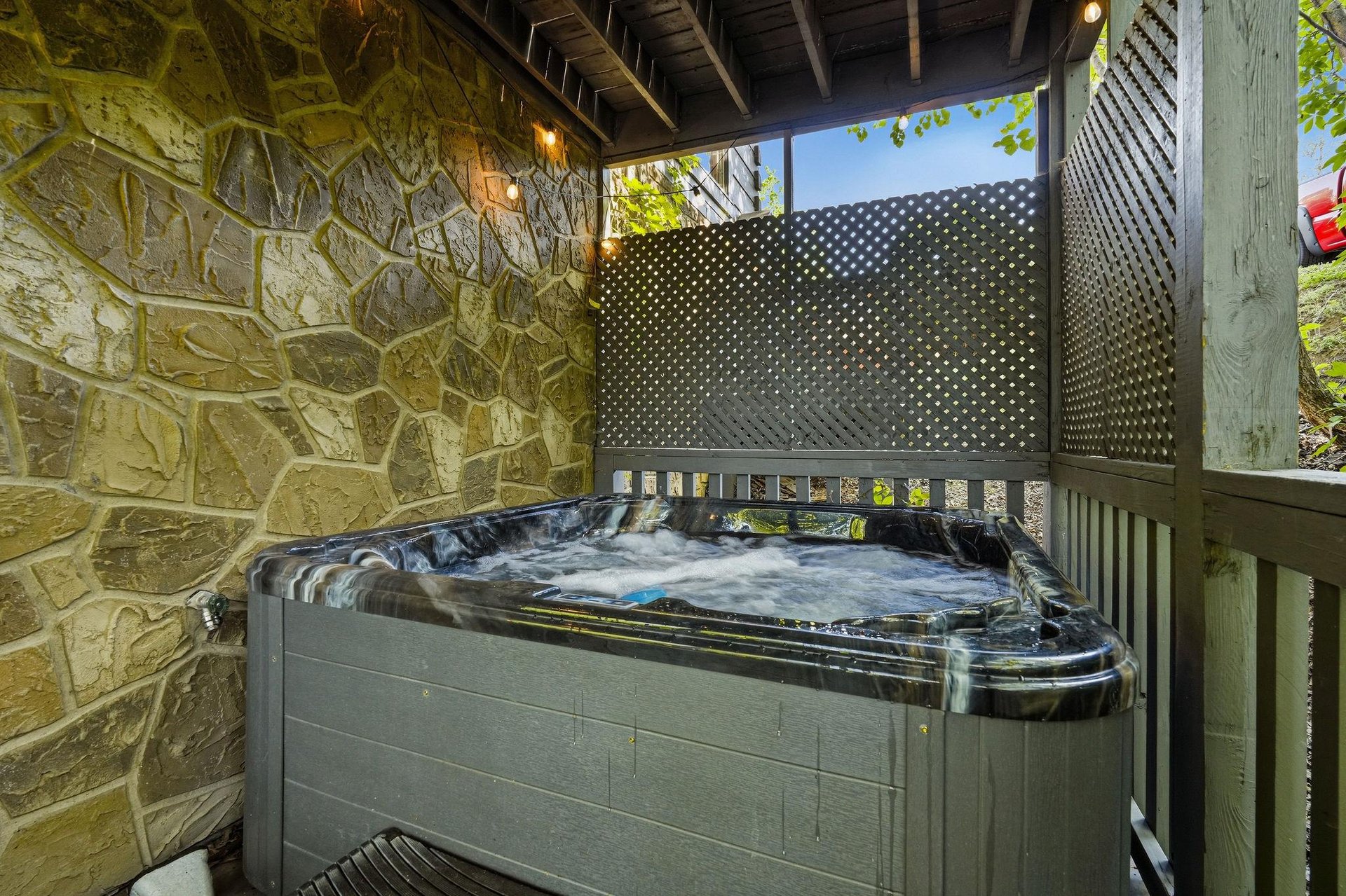 Unwind in your private hot tub, surrounded by natural stone walls and peaceful privacy screens for the ultimate relaxation experience.