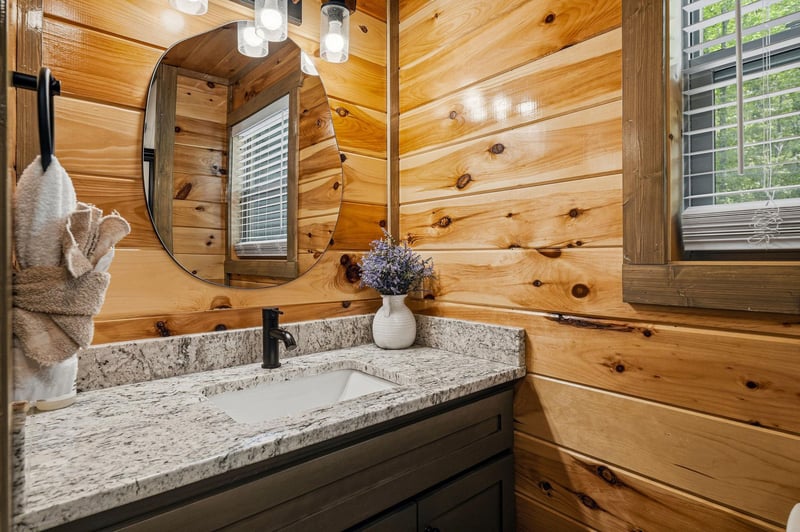 Refresh in this rusticchic bathroom where warm wood walls and granite countertops create a cozy cabin atmosphere perfect for your morning routine.
