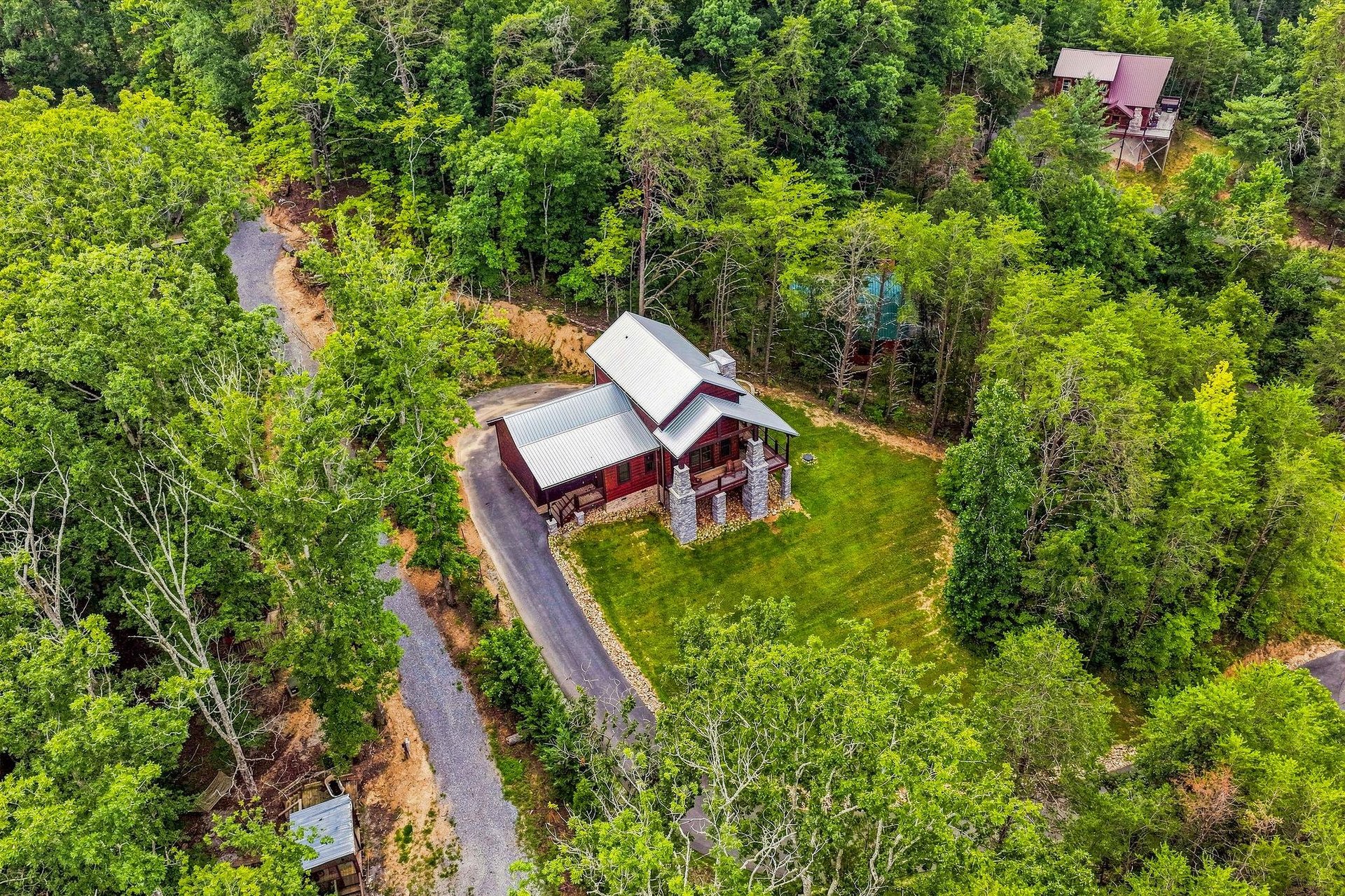 Secluded cabin retreat surrounded by lush forest canopy, offering privacy and peaceful seclusion in a natural mountain setting with convenient driveway access.