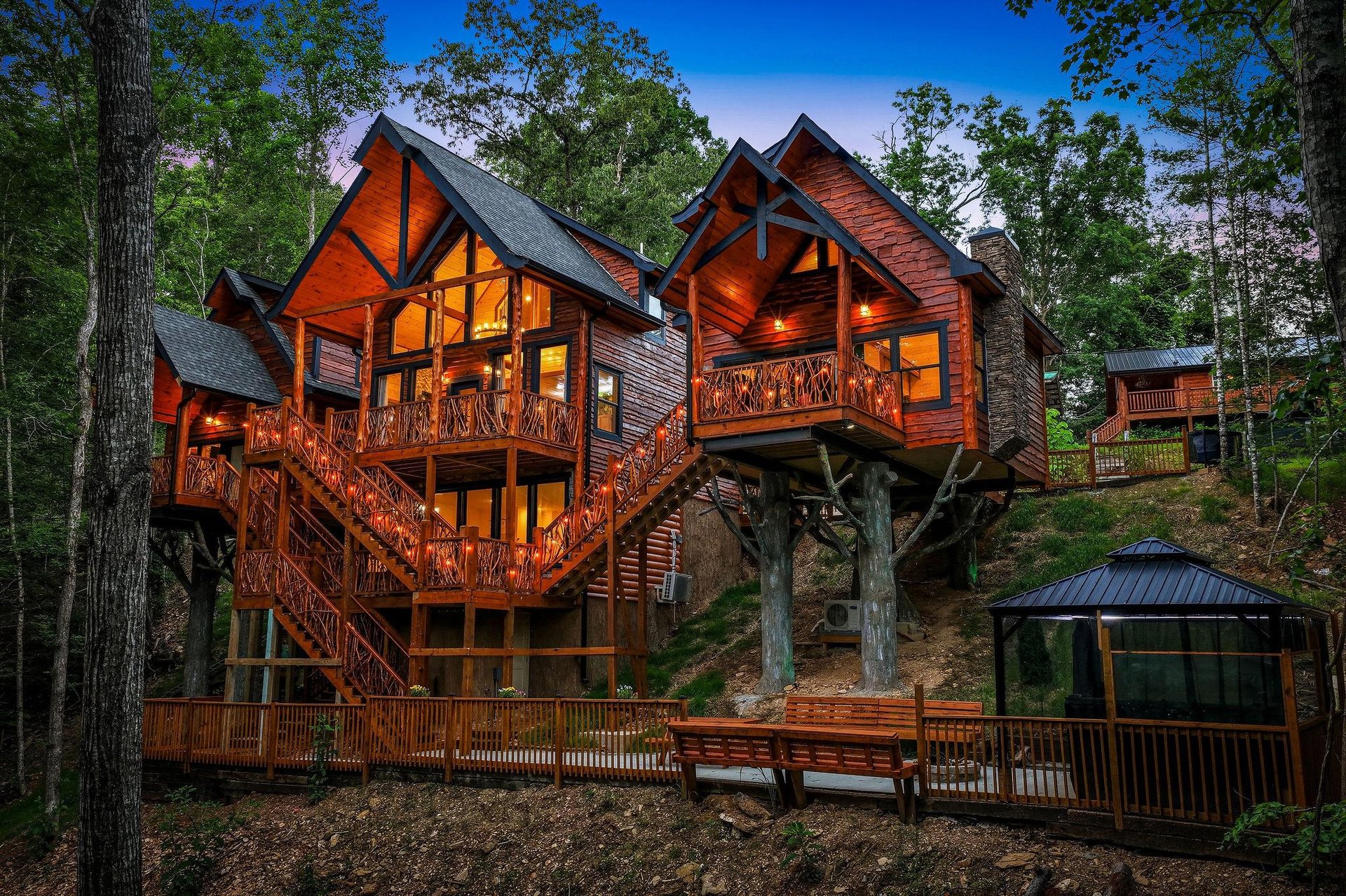 This stunning multilevel cabin nestled among towering trees offers a perfect woodland escape with warm rustic charm, expansive decks, and a private hot tub.