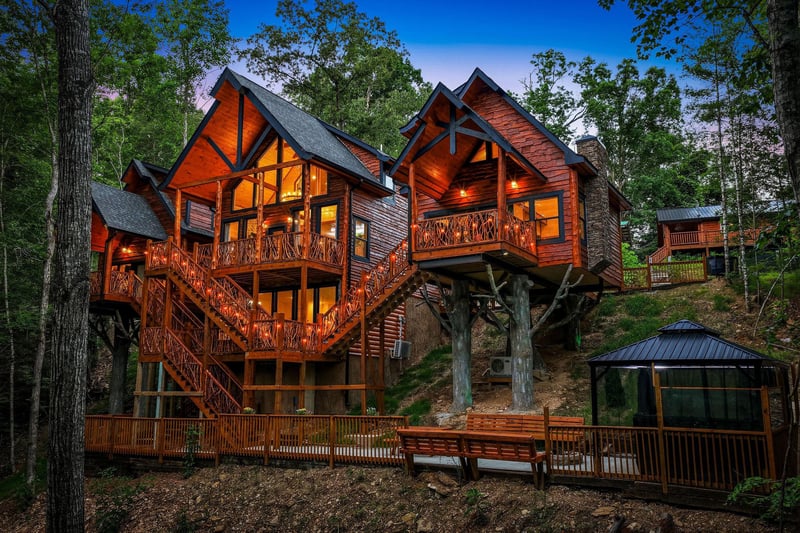 This stunning multilevel cabin nestled among towering trees offers a perfect woodland escape with warm rustic charm, expansive decks, and a private hot tub.