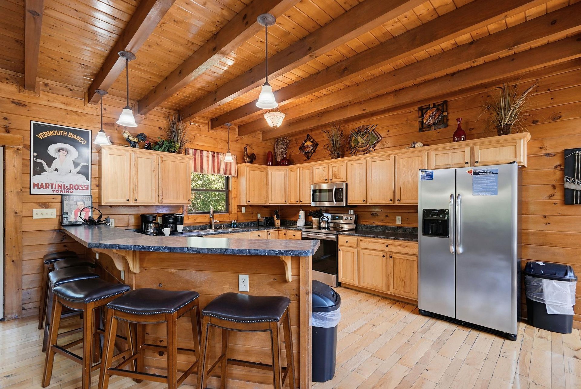 Gather around the kitchen island where rustic charm meets modern comfort, inviting you to share morning coffee and stories under soaring woodbeamed ceilings.