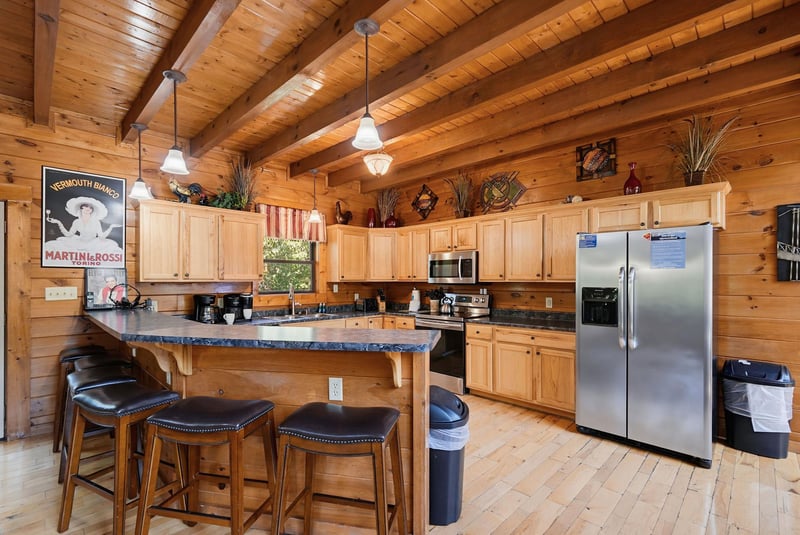 Gather around the kitchen island where rustic charm meets modern comfort, inviting you to share morning coffee and stories under soaring woodbeamed ceilings.