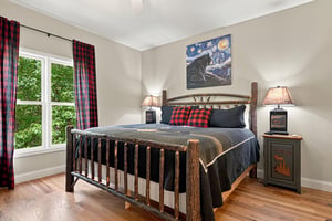 Relax in your cozy retreat featuring a handcrafted log bed, warm bedside lighting, and peaceful garden views through large windows. The rusticmeetsrefined ambiance invites restful nights in complete