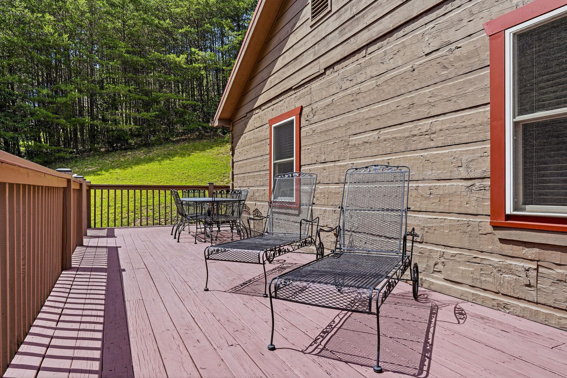 Nestled in the woods, this spacious deck offers the perfect spot to unwind with morning coffee or afternoon sunshine on comfortable lounge chairs and dining seating.