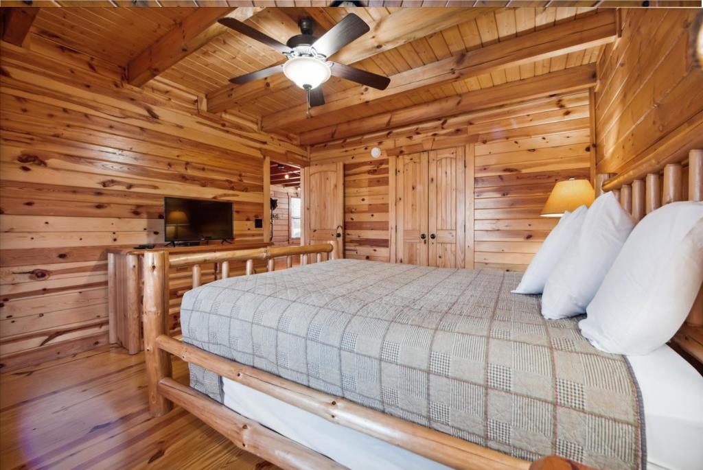 Your cozy log cabin bedroom wraps you in warm wood from floor to ceiling, featuring a rustic log bed and modern amenities.