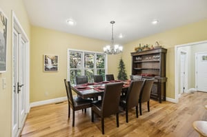 Gather around this inviting dining table, where meals become memories in a bright, cheerful space framed by garden views and warm wood tones.