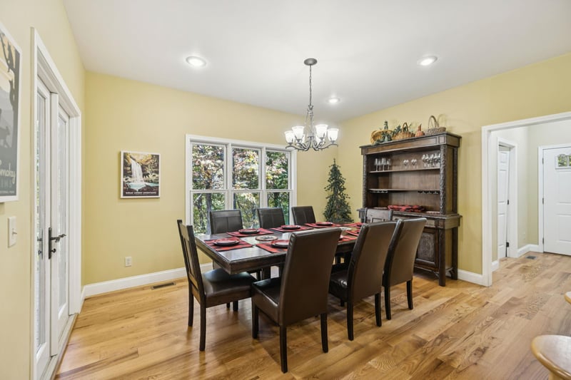 Gather around this inviting dining table, where meals become memories in a bright, cheerful space framed by garden views and warm wood tones.