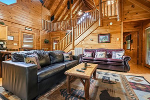 Sink into plush leather sofas surrounded by warm pine walls and rustic charm in your spacious mountain retreat living room.