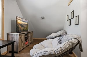 Cozy loft seating with plush comfort, warm wood accents, mountain views on screen, and peaceful minimalist decor create your perfect retreat space.