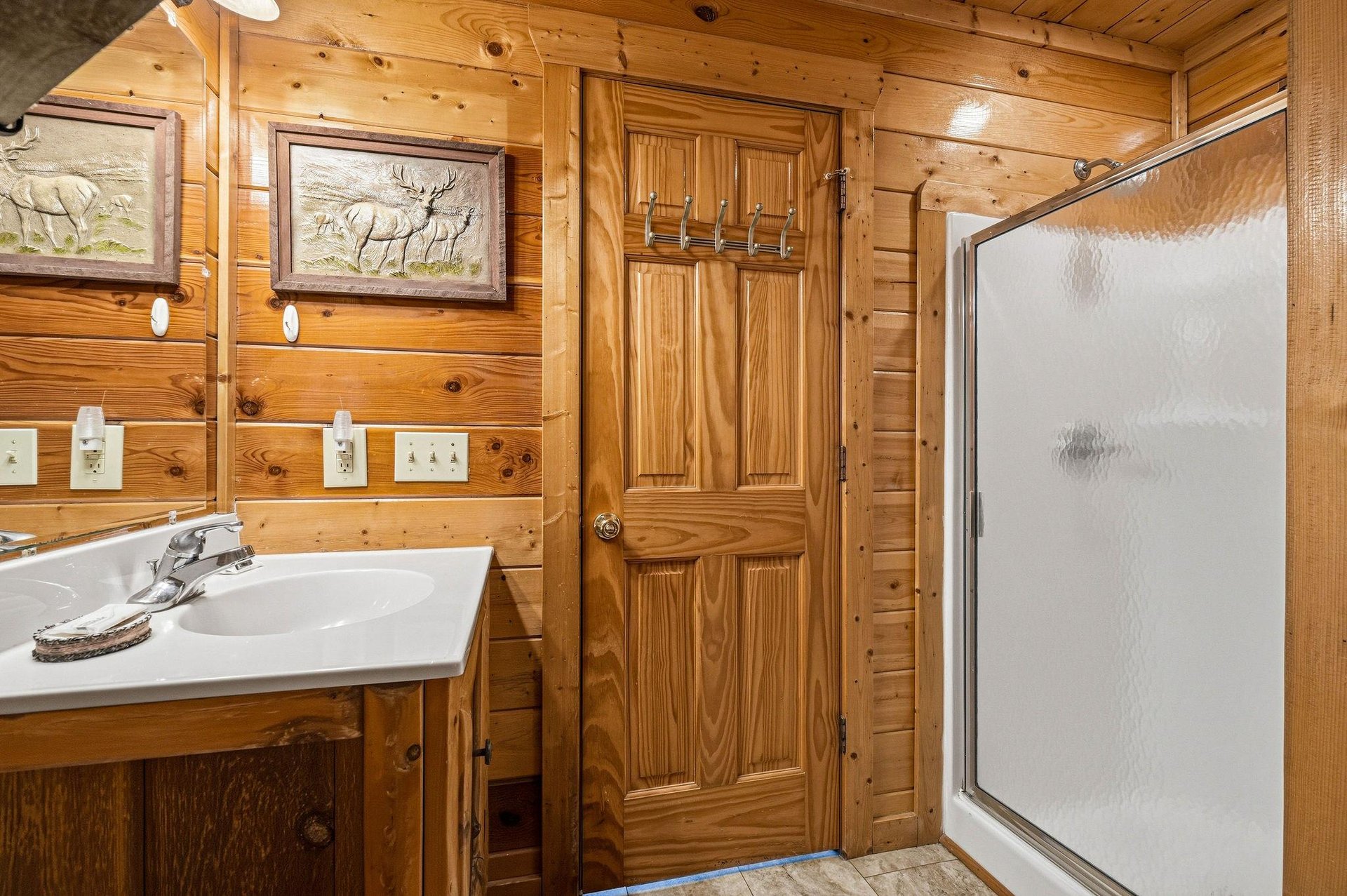Step into your rustic cabinstyle bathroom, complete with warm pine walls, wildlife artwork, and a spacious walkin shower where you can unwind after a day of adventure.
