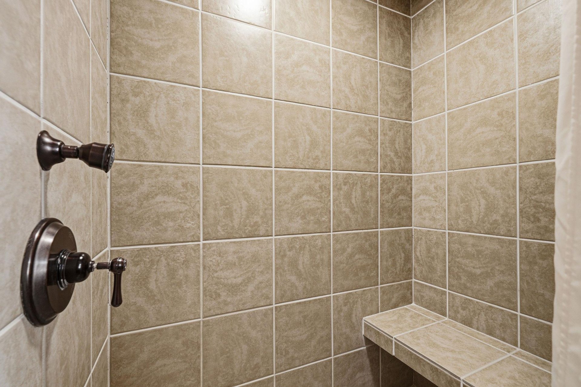 Step into your private walkin shower with elegant tiled walls and a builtin bench for ultimate relaxation.