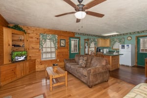 Living room with sofa, TV, and adjacent kitchen at Hideaway, a 1 bedroom cabin rental located in Pigeon Forge