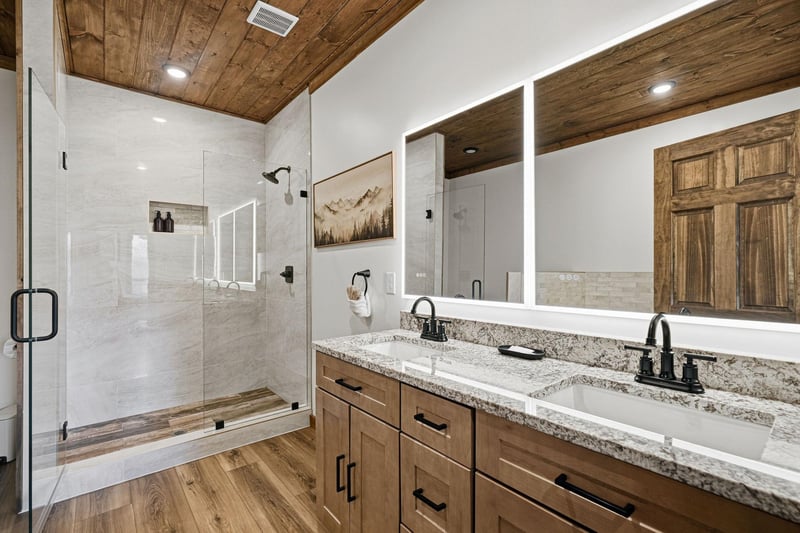 Step into your luxurious bathroom featuring dual vanities, granite counters, and a stunning walkin shower with mountain views.
