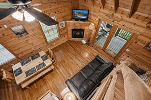 Take in the vaulted ceilings and cozy mountain charm from this lofted perspective. Wood beams frame your comfortable living space, complete with plush seating, a warm fireplace, and large windows welc