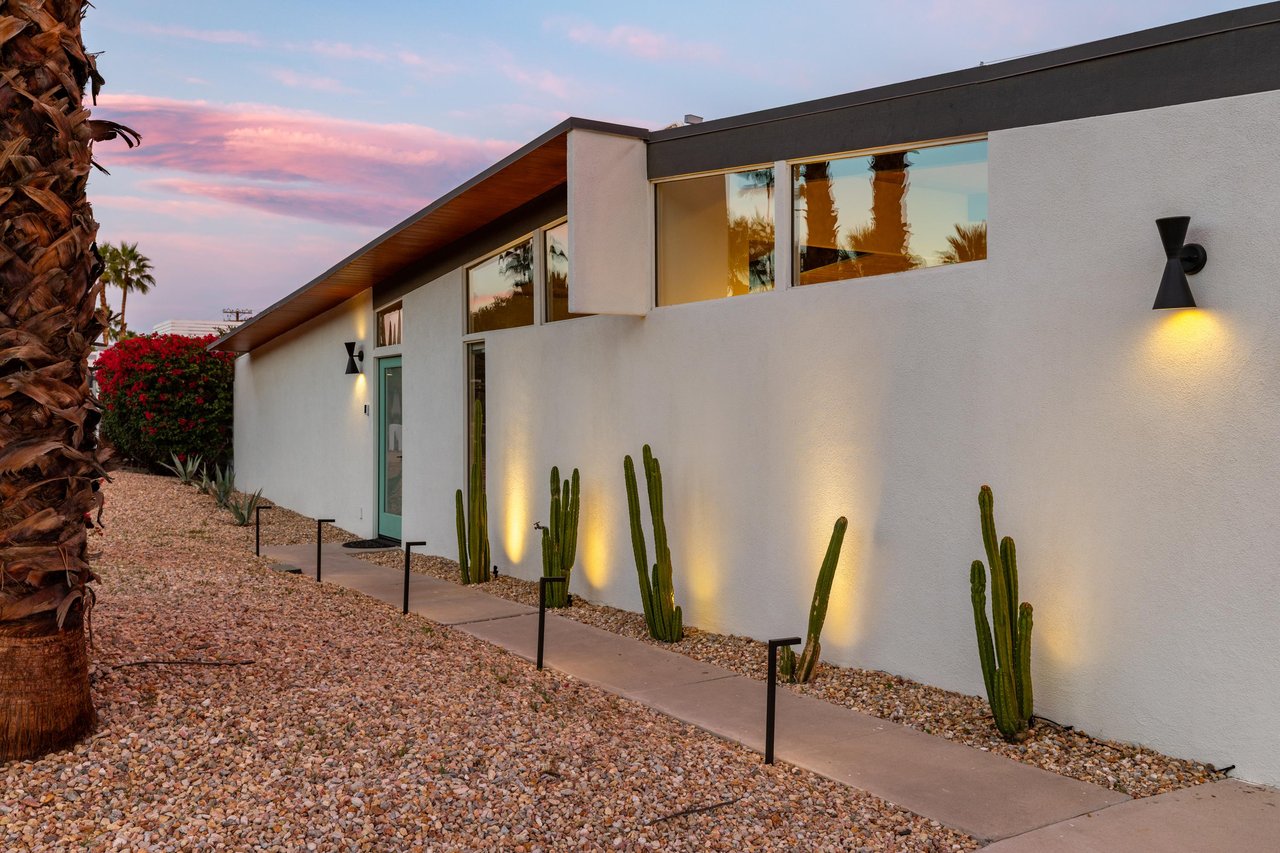 Modern desert architecture showcases clean lines and striking cacti landscaping under a painted sunset sky.