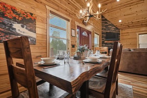 Step inside your cozy cabin where rustic charm meets modern comfort. Natural pine walls and warm lighting welcome you to gather around a beautifully set table, perfect for creating memorable moments t