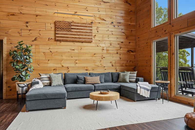 Unwind in your spacious living room with soaring woodpaneled ceilings, plush sectional seating, and floortoceiling windows framing treetop views. Natural light floods this warm, inviting space—perf