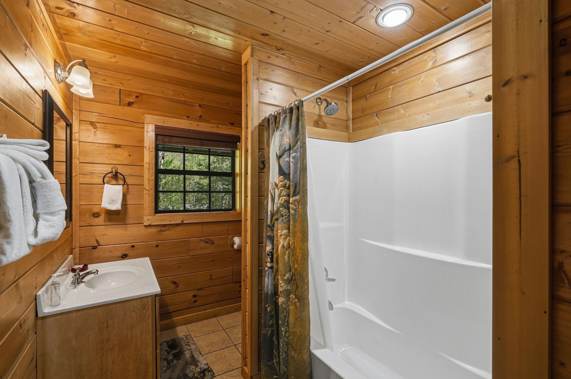 Warm wood walls surround your private bathroom retreat, complete with fresh towels and natural light streaming through the window.