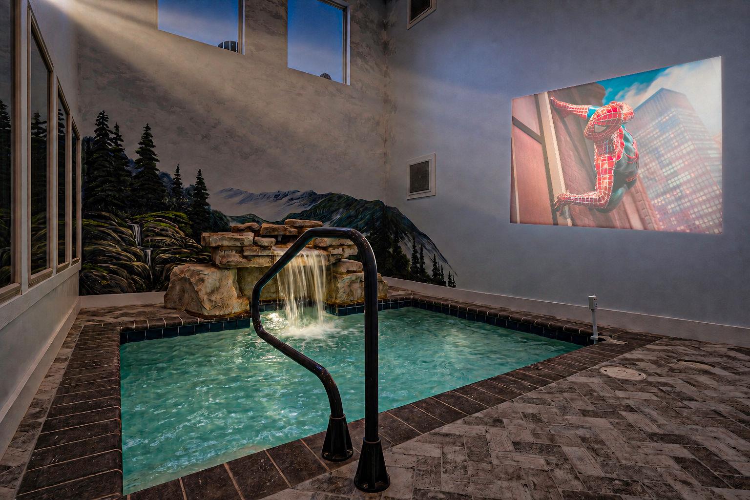 An indoor pool with waterfall feature invites you to unwind in your private retreat, complete with mountain mural and entertainment screen.
