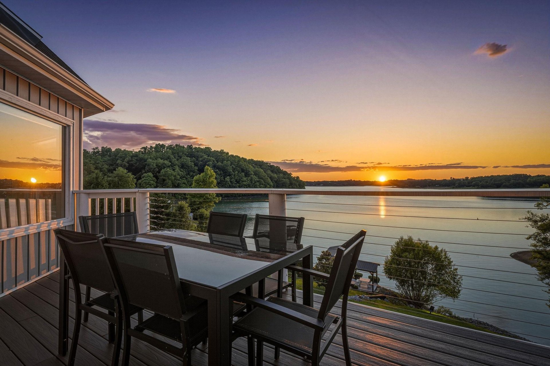 Waterfront deck showcasing a breathtaking sunset over the lake, framed by wooded islands and tranquil waters—an ideal spot for morning coffee or evening relaxation during your stay.