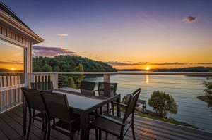 Waterfront deck showcasing a breathtaking sunset over the lake, framed by wooded islands and tranquil waters—an ideal spot for morning coffee or evening relaxation during your stay.