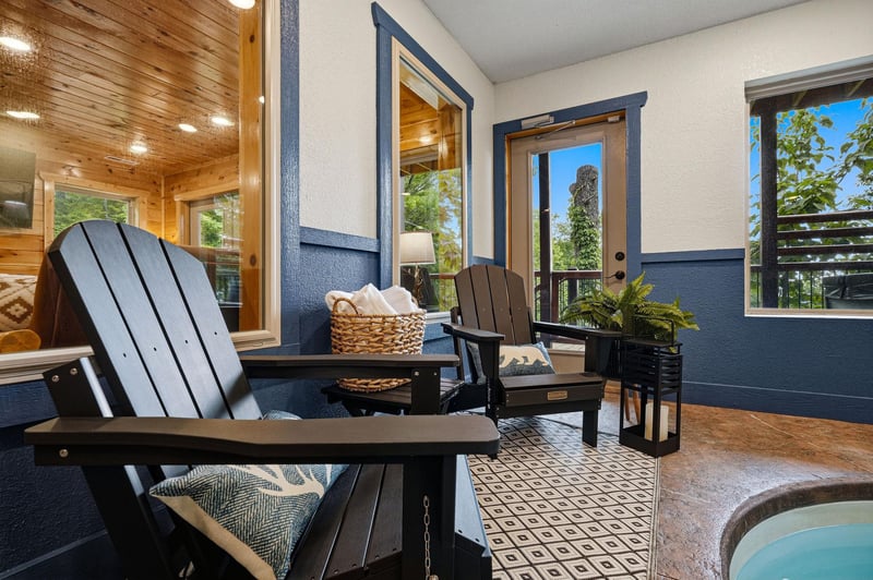 Sink into plush seating on your private patio, where tall glass doors frame leafy views and invite fresh air to flow through. A perfect spot for morning coffee or evening relaxation.