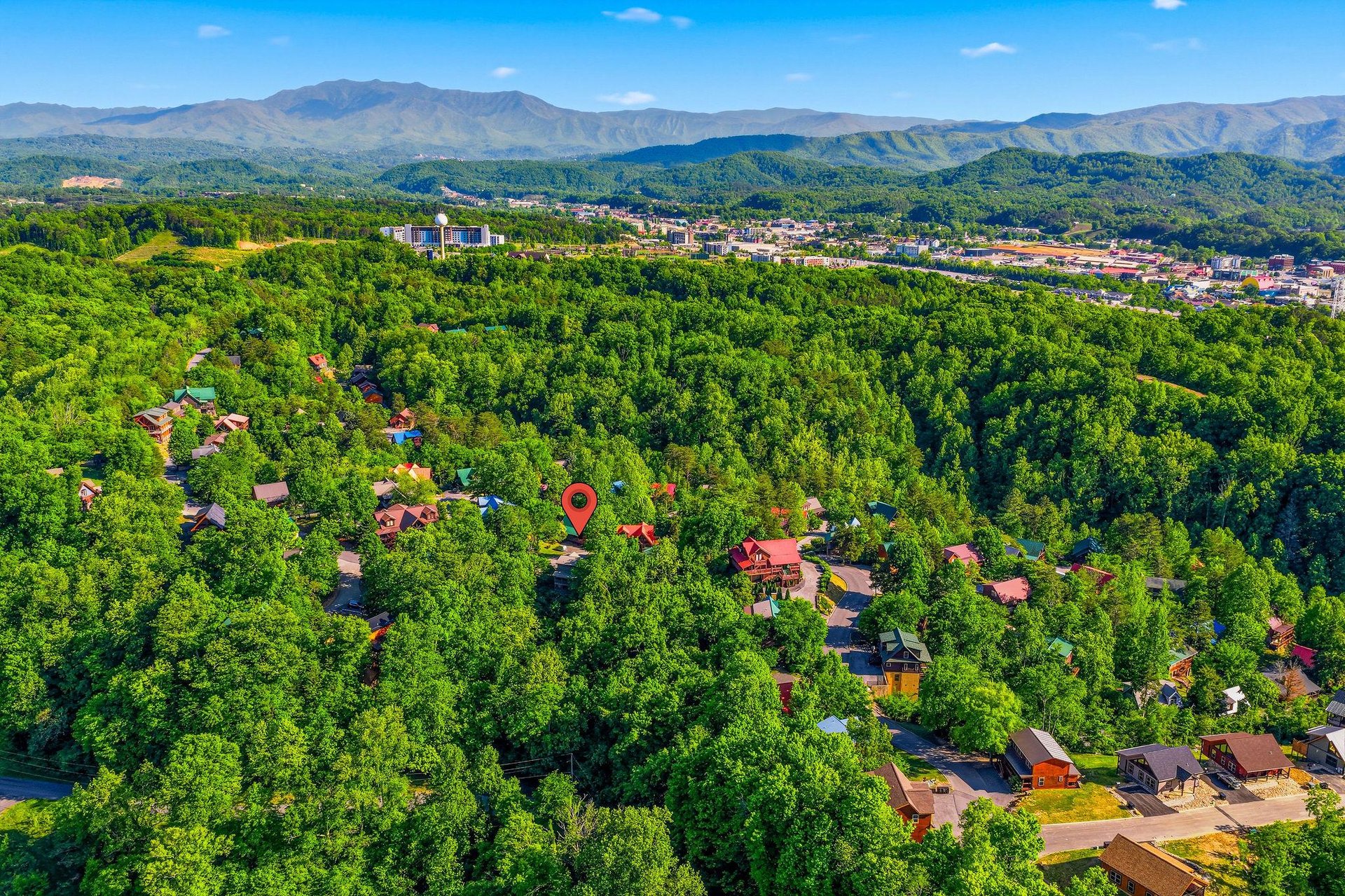 Aerial view showcasing the propertys prime location nestled among lush forests with mountain vistas and nearby city amenities.