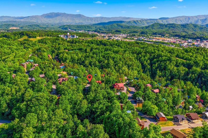 Aerial view showcasing the propertys prime location nestled among lush forests with mountain vistas and nearby city amenities.