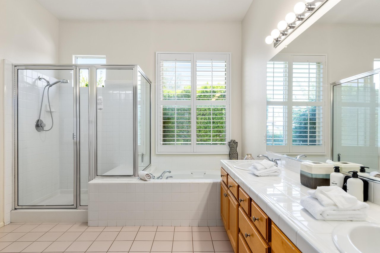 Ensuite bathroom with dual vanity sinks, stand alone tub, and stand alone shower.