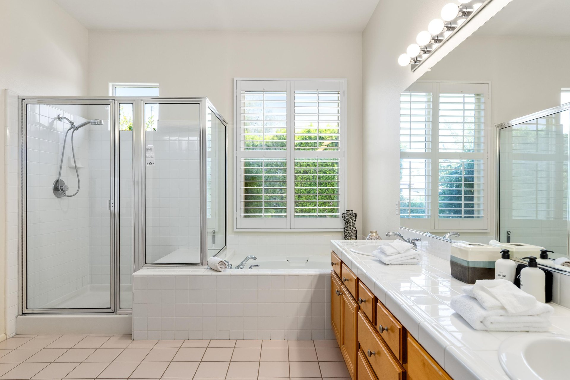Ensuite bathroom with dual vanity sinks, stand alone tub, and stand alone shower.