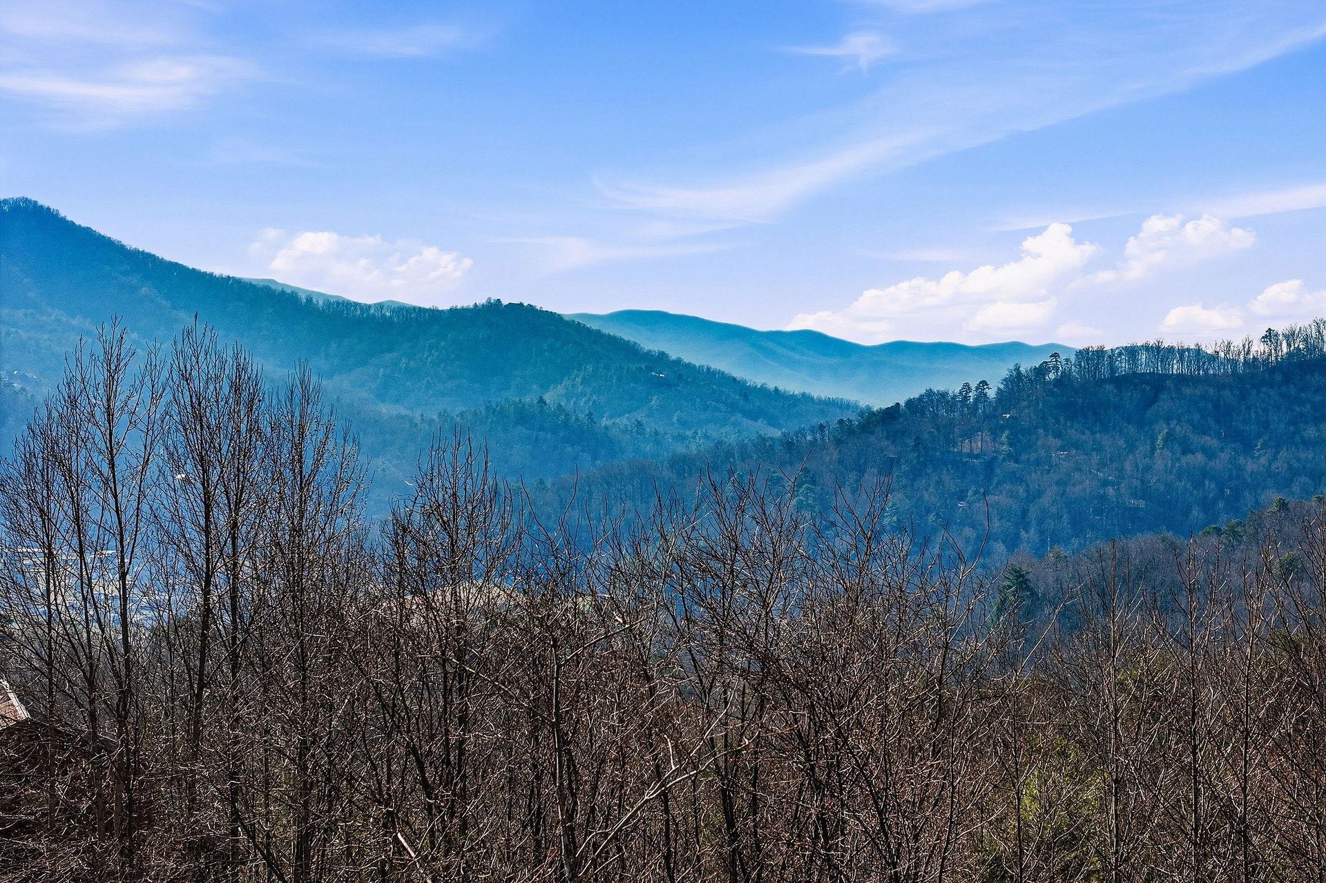 Rolling mountain ridges stretch across the horizon, creating layers of bluetinted peaks beneath a cloudy sky.