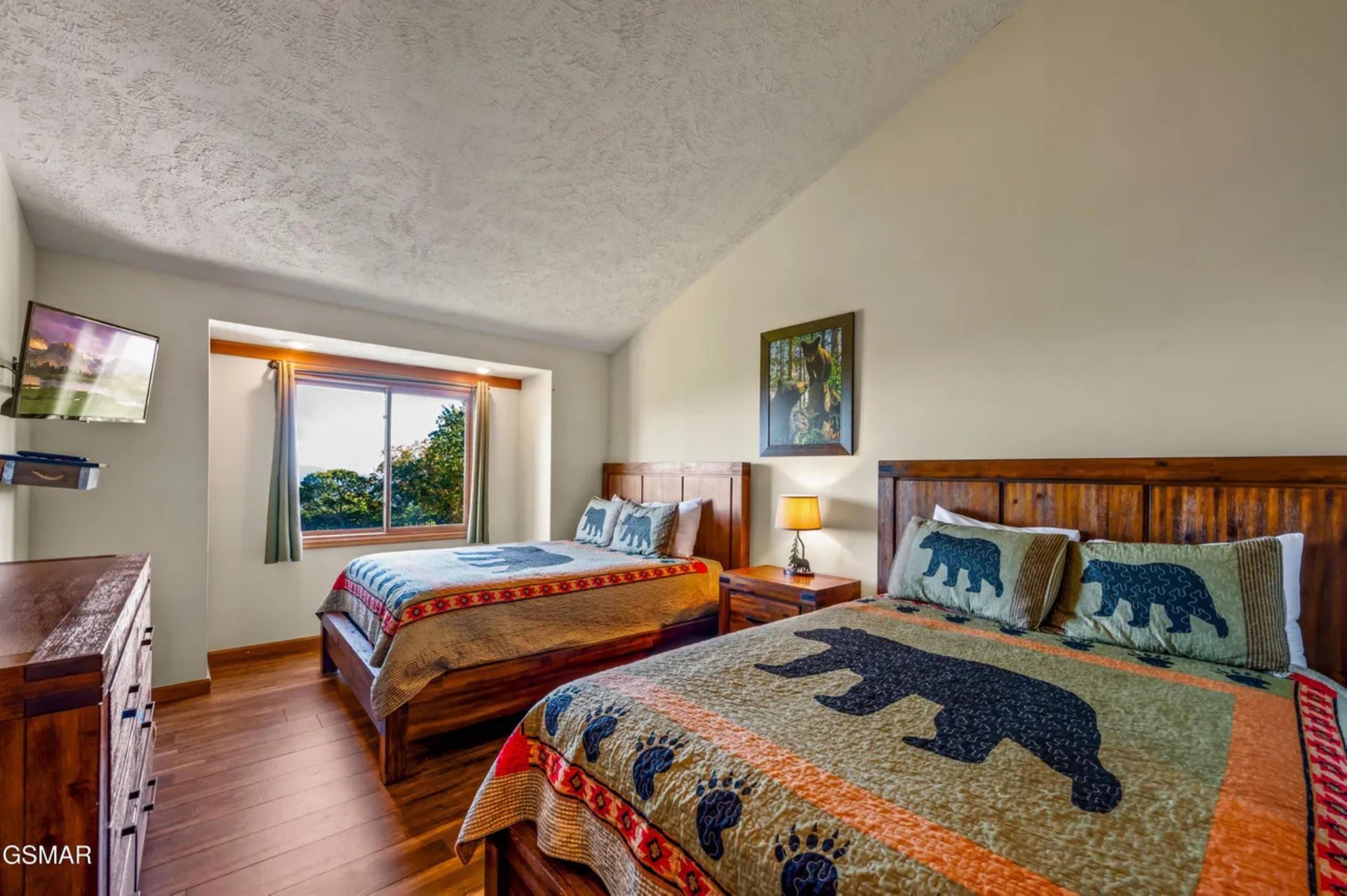 Drift off in your cozy bedroom featuring rustic wooden beds with charming bearthemed quilts and peaceful garden views.