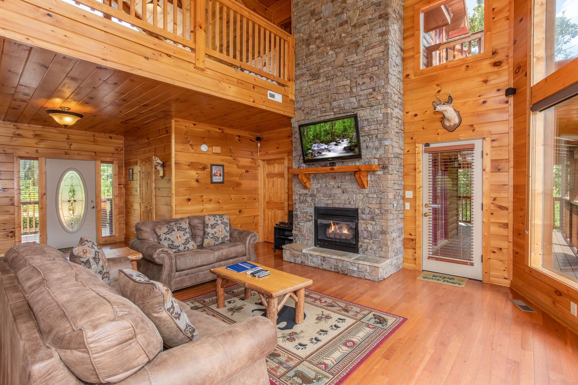 Vaulted living room with tall fireplace and deck access at Four Seasons Lodge, a 3bedroom cabin rental located in Pigeon Forge