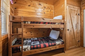 Cozy wooden bunk bed room with rustic charm and plaid quilts for your mountain getaway adventure.